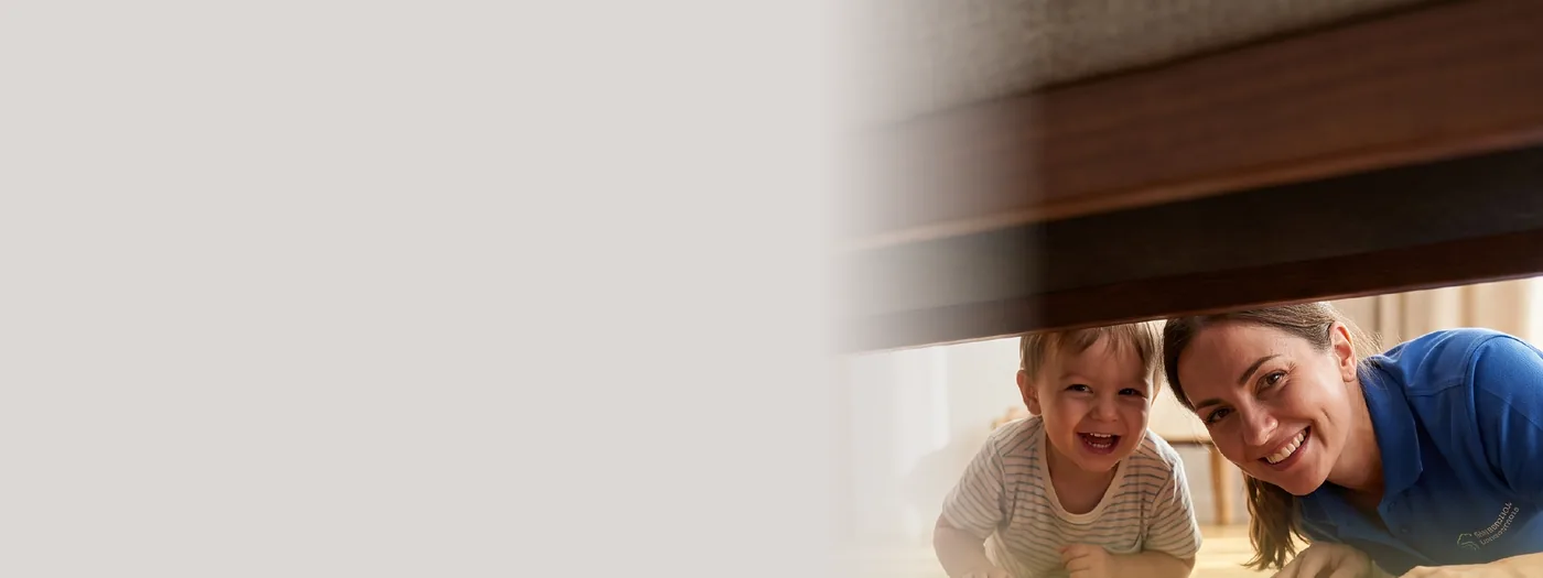 A mother and toddler smiling under a freshly cleaned table